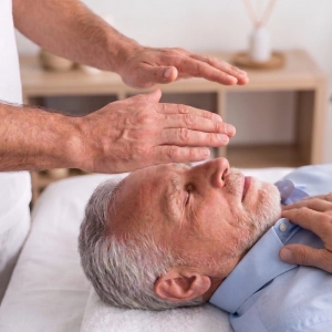 Homme adulte allongé sur une table détendu pendant une séance de soins énergétiques Reiki (magnétisme)