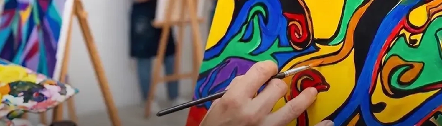 Gros plan sur la main d'une femme en train de faire un tableau pendant un atelier de peinture intuitive